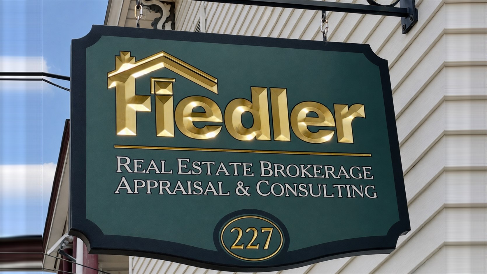 The Fiedler sign at 227 Main Street in Hackettstown — carved gold letters on green: Real Estate Brokerage, Appraisal and Consulting, with the street number 227 below