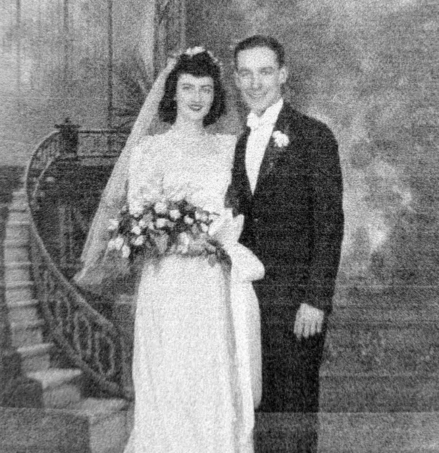 Helen and Leonard Fiedler on their wedding day in 1946 — Helen in a gown and veil holding a bouquet, Leonard in a tuxedo, on a curved staircase.