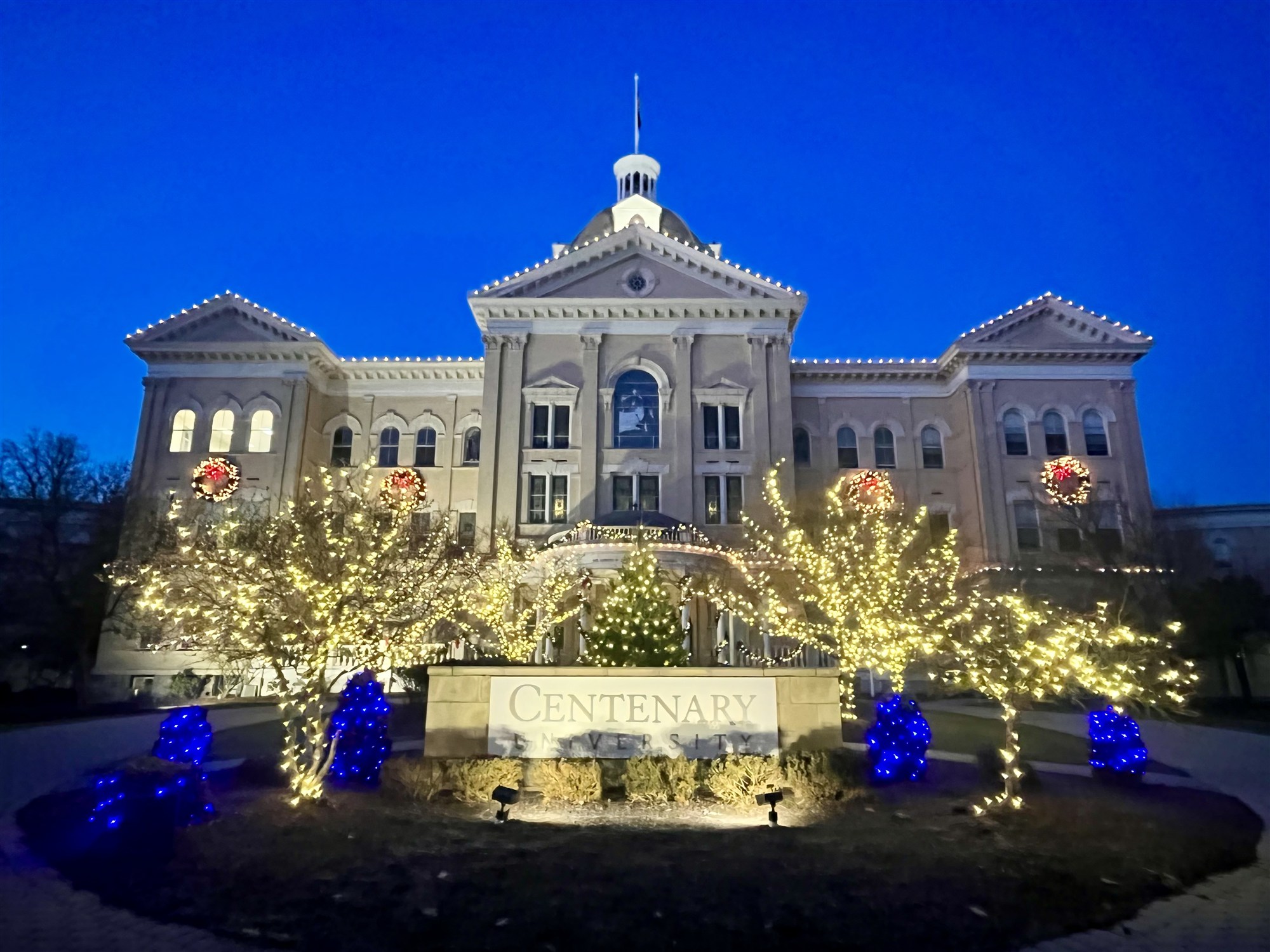 Centenary University wrapped in Christmas lights at blue hour.