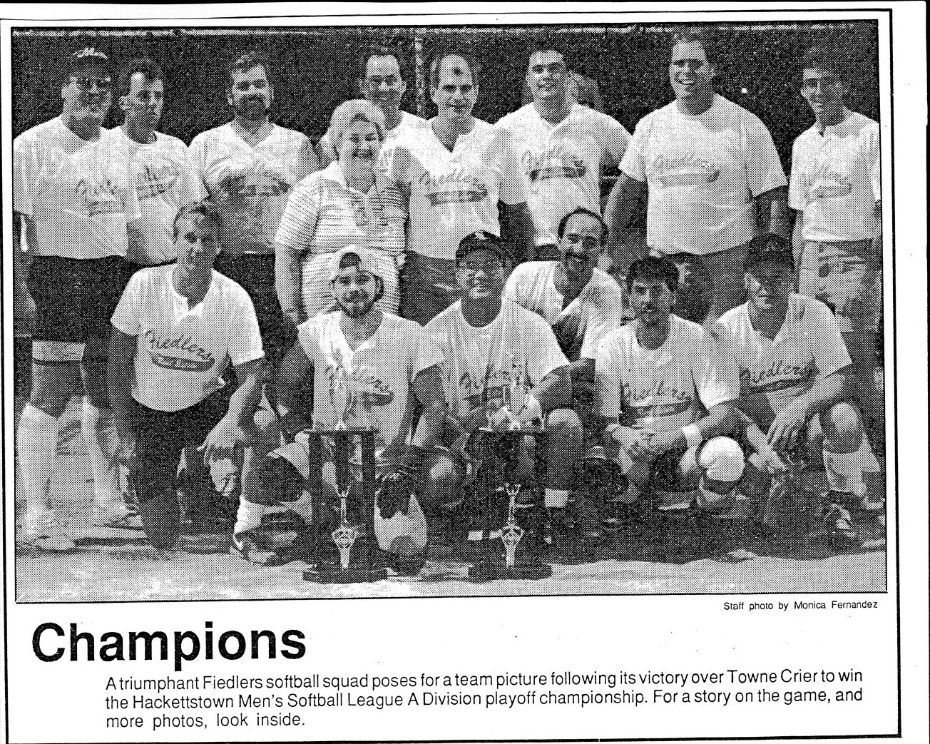 A newspaper clipping headed Champions: the Fiedlers softball squad posed on the field with two trophies at their feet, above a caption about the playoff win over Towne Crier.
